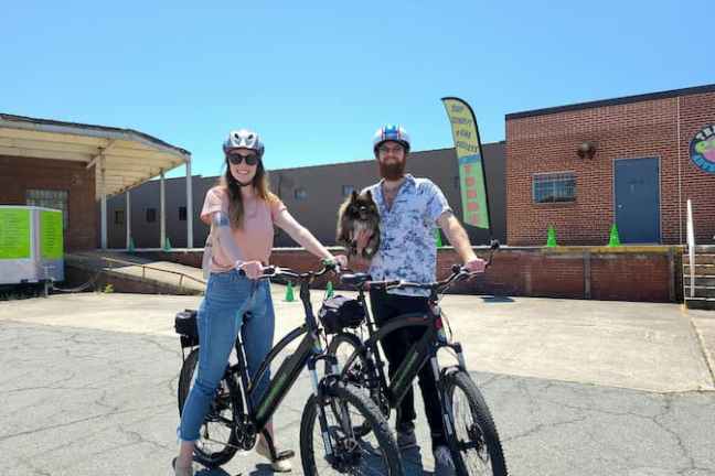 a man and woman riding on the back of a bicycle