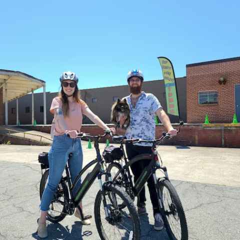 a man and woman riding on the back of a bicycle
