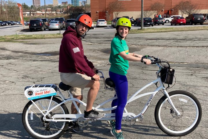 a little girl riding on the back of a bicycle