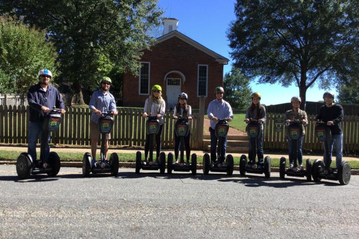People on Segway PTs in front of a brick house