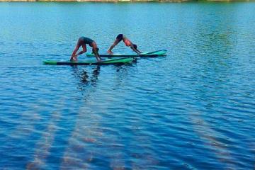 People in downward dog on SUP board