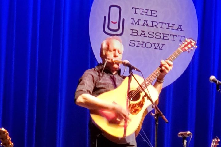 a person sitting on a stage in front of a curtain